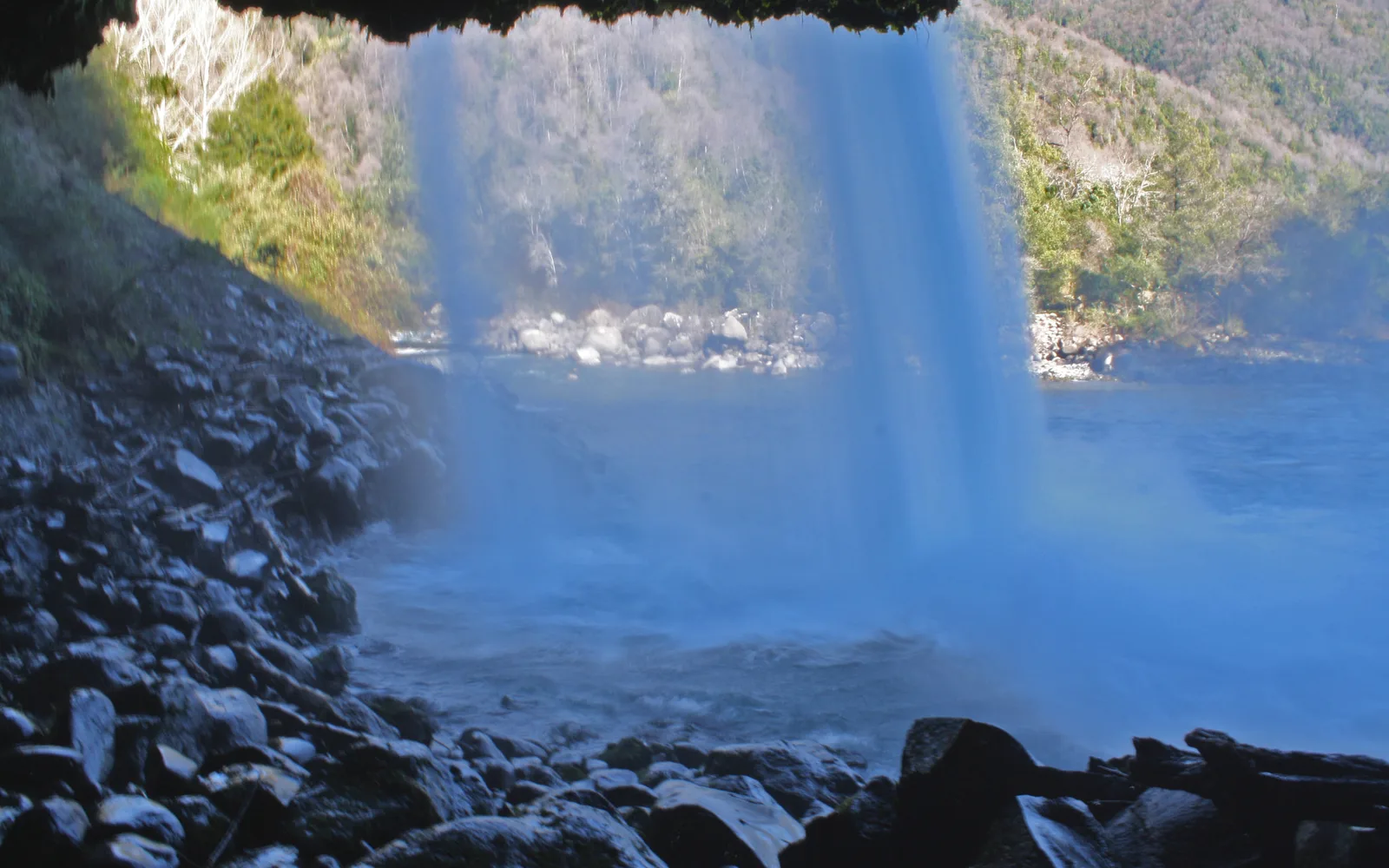 A cave with a waterfall flowing over stones, showing the natural underground water features