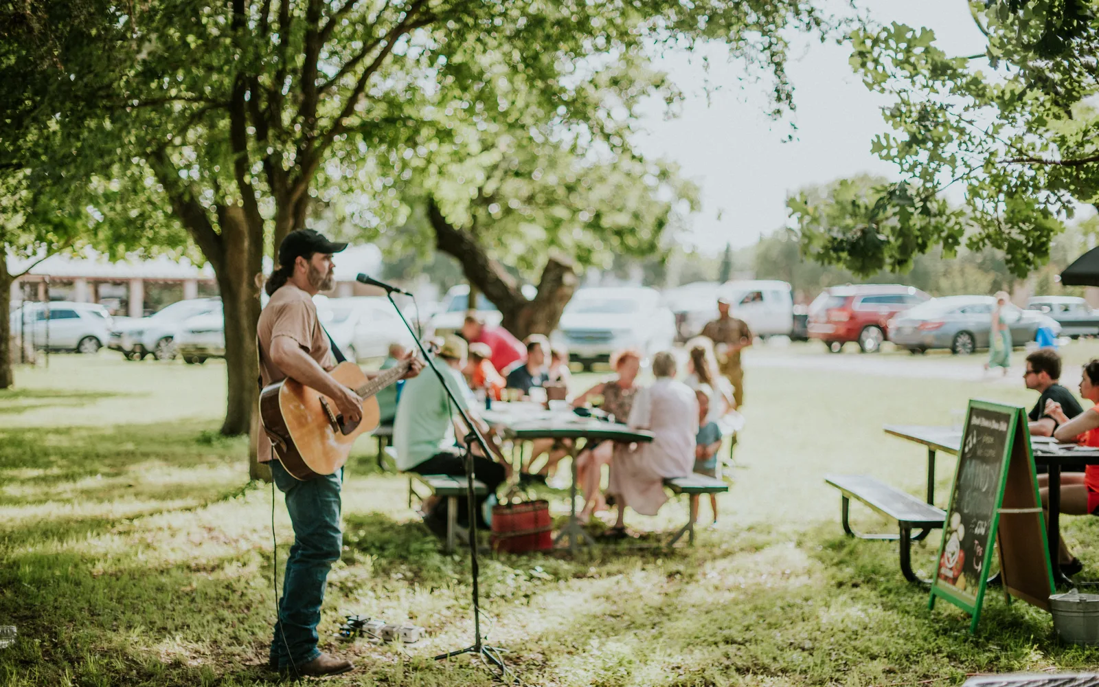 A performers singing at a farmers market event with seated audience members listening